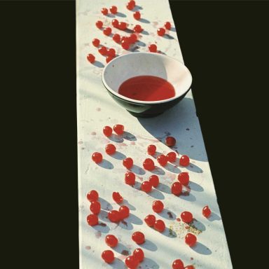 Tomates cherry dispersos en una mesa, con un bol de salsa en el centro.