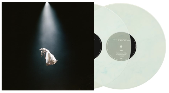 Una figura vestida de blanco bajo un rayo de luz en un fondo oscuro, con discos de vinilo.