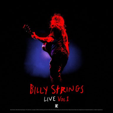Billy Strings toca la guitarra en un escenario con luces de colores.