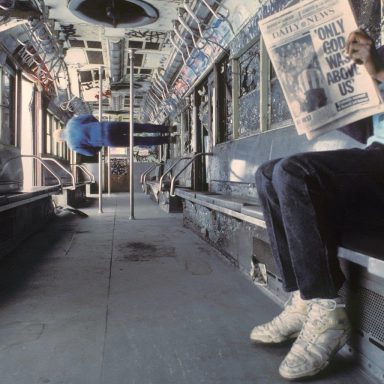 Interior de un autobús vacío, con una persona leyendo un periódico y otra sentado al fondo.