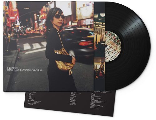 Una mujer elegante en una calle iluminada de una ciudad, junto a un vinilo.