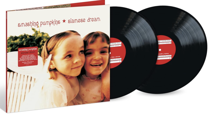 Dos niñas sonrientes junto a un álbum de vinilo.